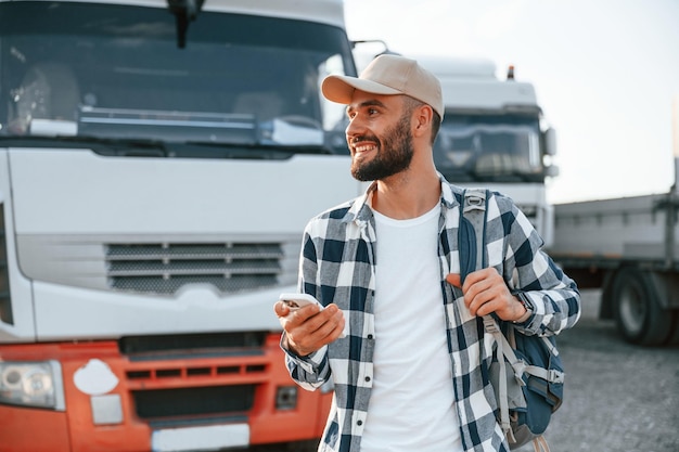 Standing outdoors Young truck driver is with his vehicle at daytime