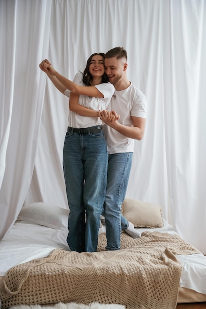 Standing and playing on the bed Young couple are together at home