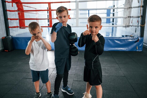 Standing and posing for a camera boys training boxing in the gym together