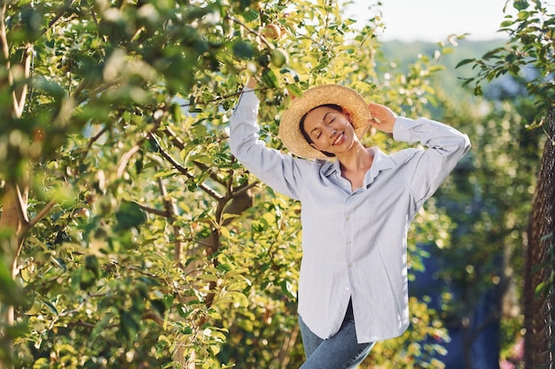 Standing and posing Young cheerful woman is in the garden at daytime