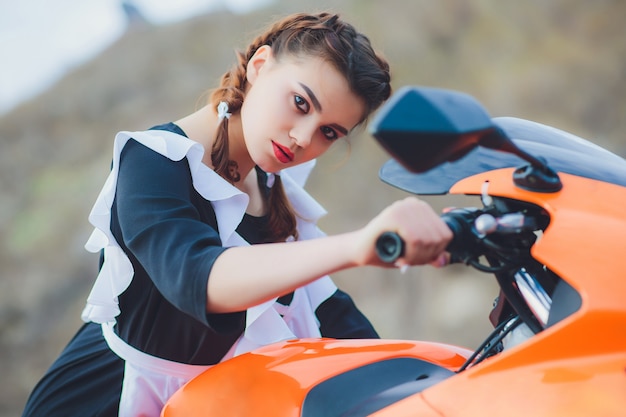 Standing schoolgirl with typical navy white uniform apron sits on motorcycle