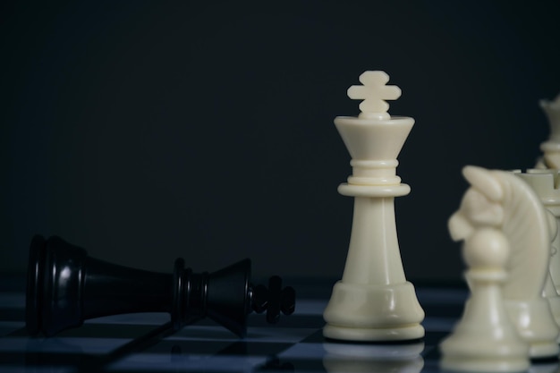 立っている白いチェスの駒と横たわっている黒い王
