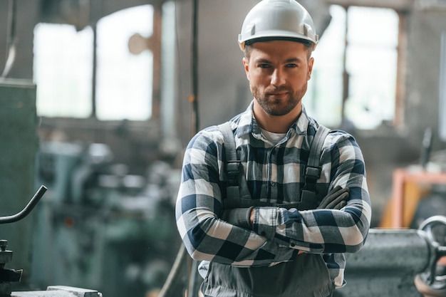 Standing with arms crossed Factory male worker in uniform is indoors