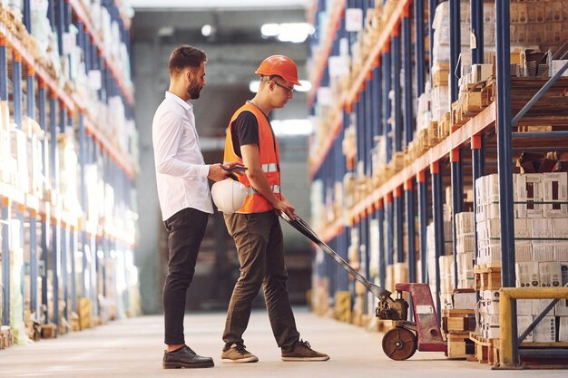 Standing and working together Two men in storage is in the warehouse