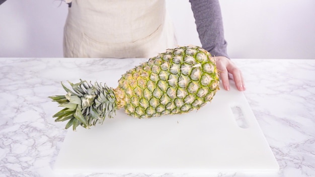 Stap voor stap. Ananas snijden op een witte snijplank.