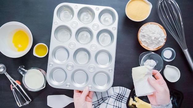 Stap voor stap. Beboterde metalen cupcakevorm om maïsbroodmuffins te bakken.