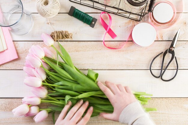 Stap voor stap. Bloemist die roze tulpen in boeket verpakken.