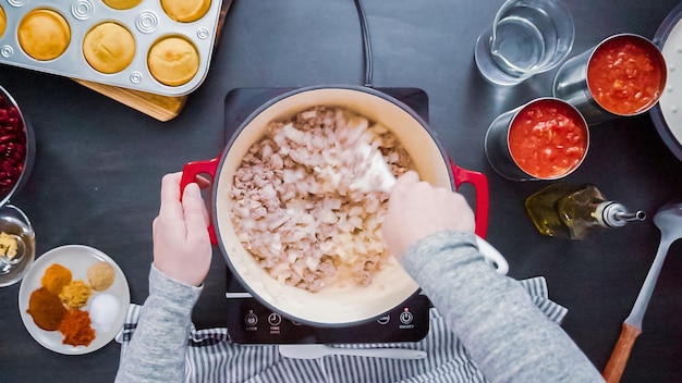 Stap voor stap. Bovenaanzicht. Koken kalkoen chili in geëmailleerde gietijzeren bedekte Nederlandse oven.