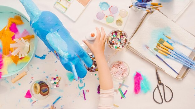 Stap voor stap. ecorating geschilderd papier-maché eenhoorn met papieren bloemen en juwelen.