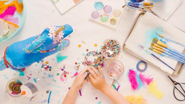 Stap voor stap. ecorating geschilderd papier-maché eenhoorn met papieren bloemen en juwelen.