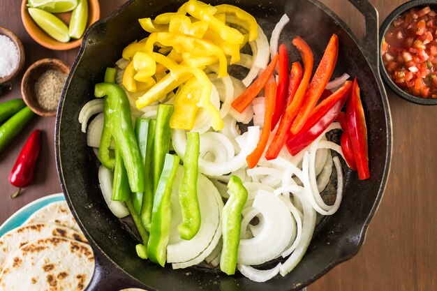 Stap voor stap. Frituur van verse groenten in grote gietijzeren pan voor steak fajitas.