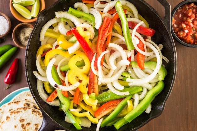 Stap voor stap. Frituur van verse groenten in grote gietijzeren pan voor steak fajitas.