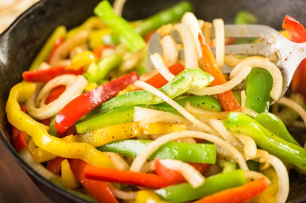 Stap voor stap. Frituur van verse groenten in grote gietijzeren pan voor steak fajitas.