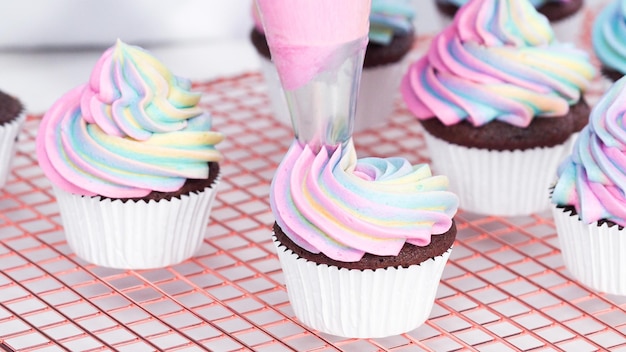 Stap voor stap. Glanzende eenhoorn-chocolade-cupcakes met regenboogkleurige buttercream frosting.