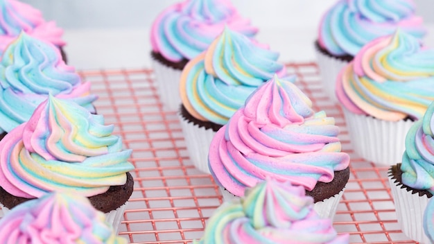 Stap voor stap. Glanzende eenhoorn-chocolade-cupcakes met regenboogkleurige buttercream frosting.