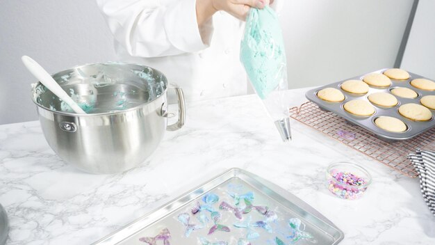 Stap voor stap. Het mengen van ingrediënten in de keukenmixer om buttercream frosting te maken voor vanille cupcakes met zeemeermin thema.