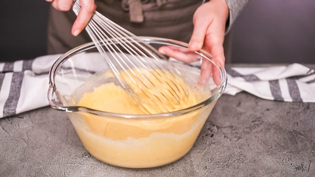 Stap voor stap. Ingrediënten samen mengen in glazen mengkom voor pittige jalapeno maïsbroodmuffins.