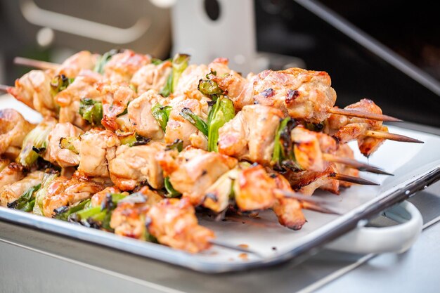 Stap voor stap. Kip yakitori op een wit metalen dienblad naast een buitengasgrill.