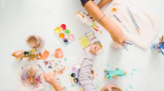 Stap voor stap. Kleine meisjes schilderen eenhoorn van papier-maché met acrylverf.