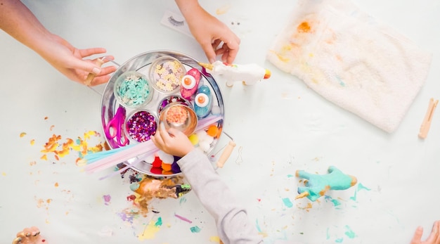 Stap voor stap. Kleine meisjes schilderen eenhoorn van papier-maché met acrylverf.