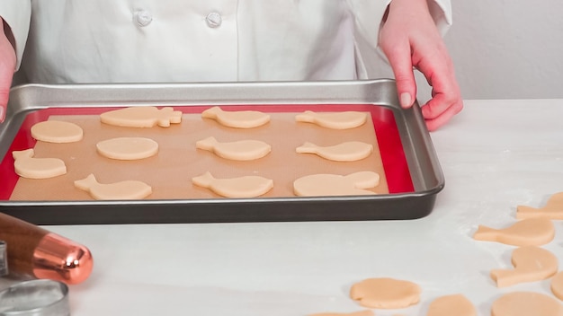 Stap voor stap. Ongebakken Pasen-suikerkoekjes gerangschikt voor het bakken op een bakplaat.