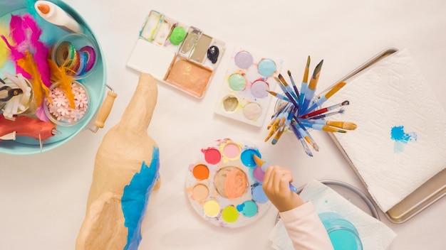 Stap voor stap. Papier mache eenhoorn schilderen met blauwe verf.