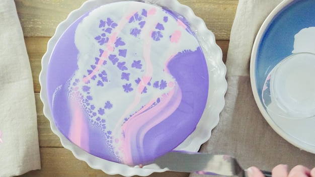 Stap voor stap. Pastre shef maakt mousse cake met paarse spiegelglazuur en versierd met chocolade roze bloemen.