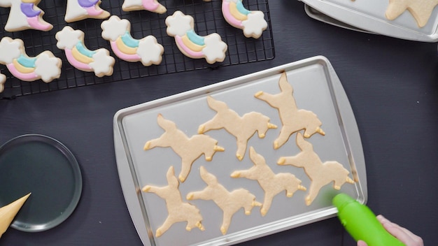 Stap voor stap. Plat leggen. Eenhoornsuikerkoekjes versieren met royal icing op bakplaat.