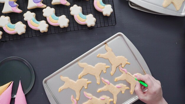 Stap voor stap. Plat leggen. Eenhoornsuikerkoekjes versieren met royal icing op bakplaat.