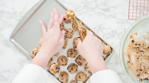 Stap voor stap. Plat leggen. Zelfgemaakte chocoladekoekjes met metalen deeglepel op de bakplaat scheppen.