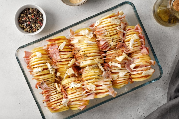 Stap voor stap recept van aardappelschotel met spekham Aardappelschijfjes in een glazen ovenschaal Ongekookt