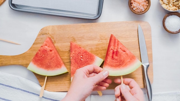 Stap voor stap. Schuif de houten popstick in de watermeloenloonwig om watermeloenijs te laten knallen.