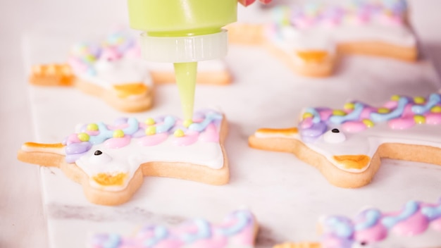 Stap voor stap. Suikerkoekjes in unocrn-vorm versieren met royal icing voor een verjaardagsfeestje voor kleine meisjes.