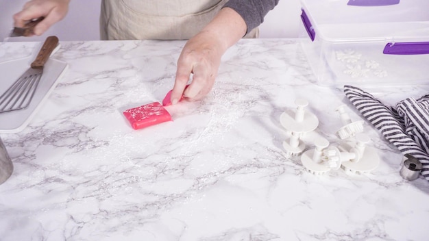 Stap voor stap. We rollen onze roze fondant op een marmeren aanrechtblad.