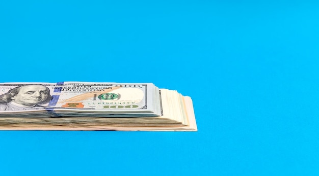 Stapel Amerikaanse dollarbiljetten op de blauwe achtergrond