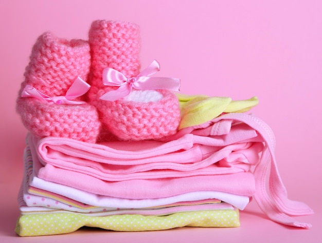 Stapel babykleertjes op roze achtergrond