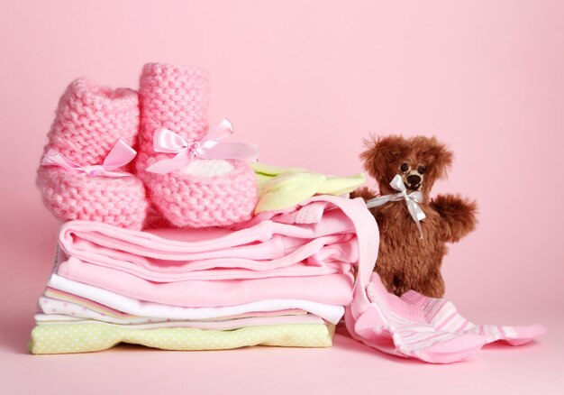 Stapel babykleertjes op roze achtergrond