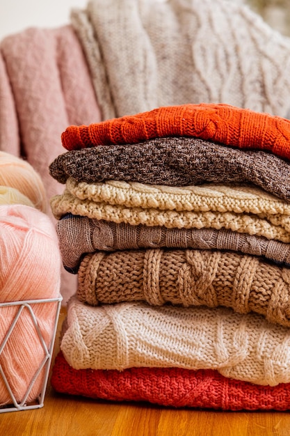 Stapel beige wollen kleding op een witte achtergrond warme gebreide truien en sjaals zijn op één hoop gevouwen