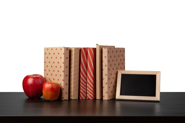 Stapel boeken en appel op tafelblad tegen witte achtergrond