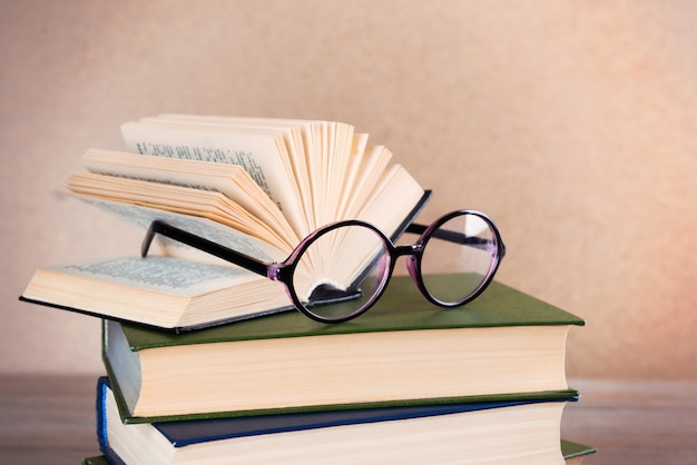 Stapel boeken en brillen erop op houten tafel, close-up