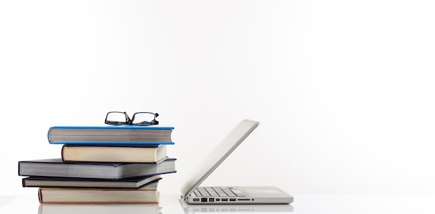 Stapel boeken en een laptop op witte achtergrond