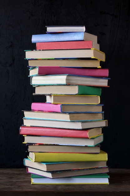 Stapel boeken in de gekleurde dekking op de lijst op de achtergrond van een schoolbord.