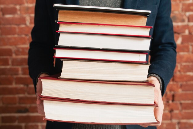 Stapel boeken in mannelijke handen close-up.