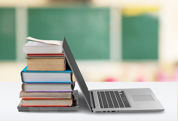 Stapel boeken met laptop op tafel