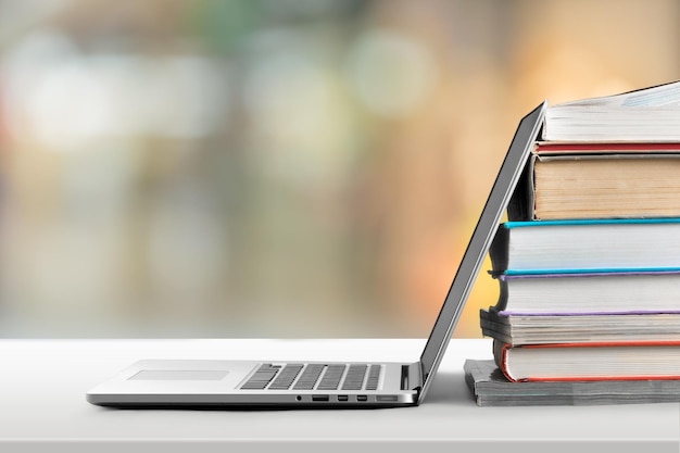 Stapel boeken met moderne laptop op tafel