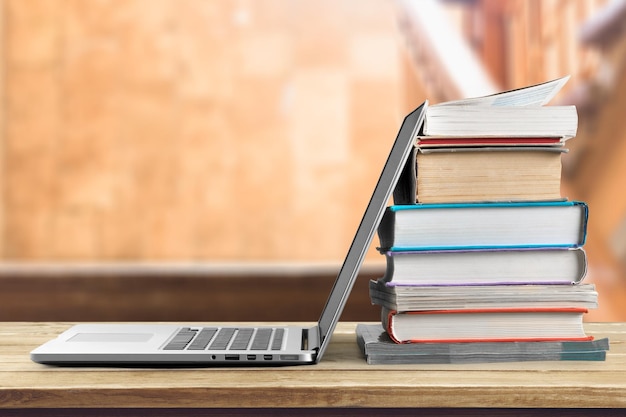 Stapel boeken met moderne laptop op tafel