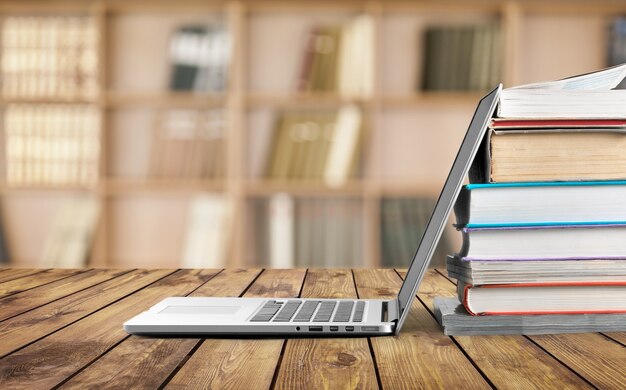 Stapel boeken met moderne laptop op tafel