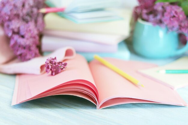 Stapel boeken open notitieblok potloden kopje thee en verse lila bloemen terug naar school concept