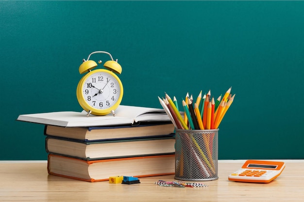 Stapel boeken potloden en klok onderwijs en leer achtergrond