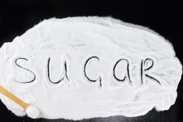 Stapel druivensuiker met de inscriptie Sugar op een zwarte achtergrond